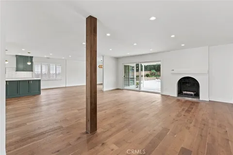 a view of an empty room with wooden floor and a fireplace