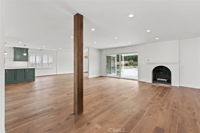 a view of an empty room with wooden floor and a fireplace