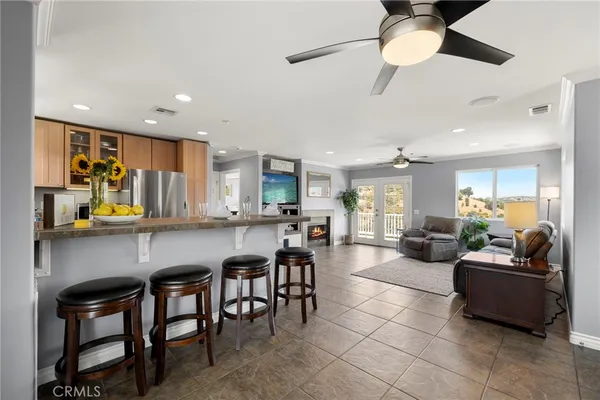 a kitchen with stainless steel appliances granite countertop a refrigerator a sink dishwasher a dining table and chairs with wooden floor