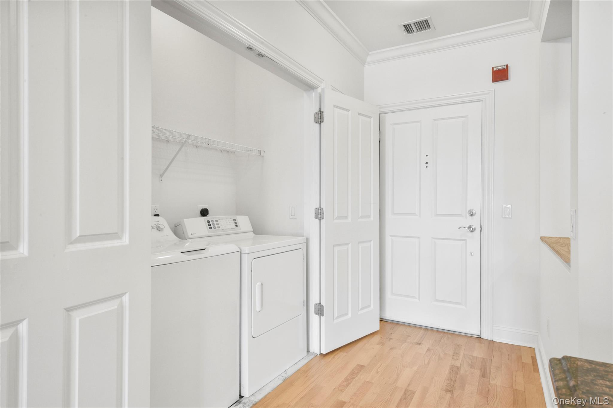55 1st Street, Unit 207 Pelham, NY 10803 - Photo 19 of 23 Laundry room with ornamental molding, light wood-type flooring, and washer and dryer