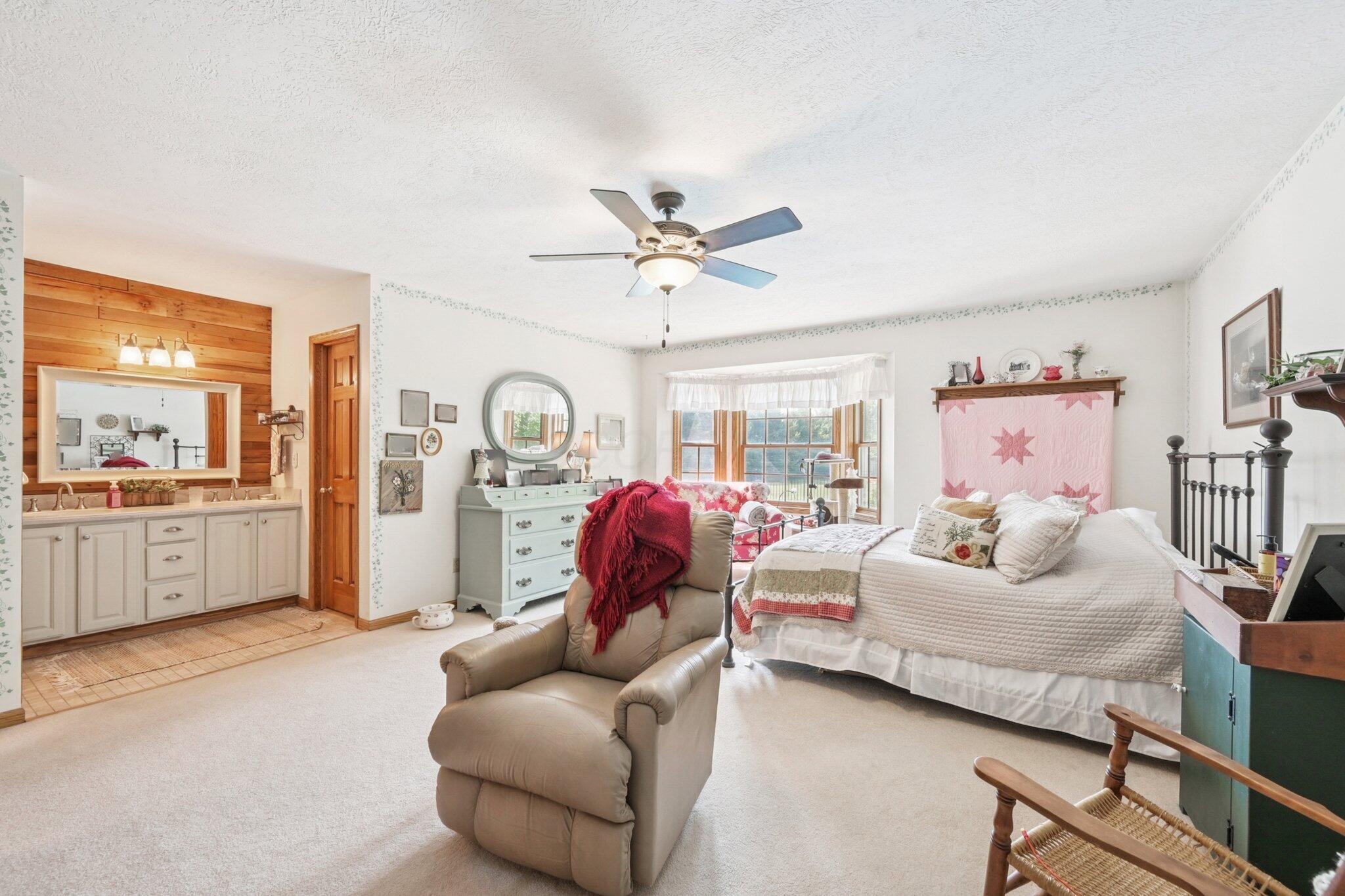 7700 Plumb Road Galena, OH 43021 - Photo 62 of 94 Primary suite with open vanity area, ceiling fan, and large layout—ideal for relaxing and unwinding at the end of the day.