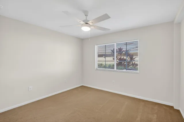 an empty room with window and ceiling fan