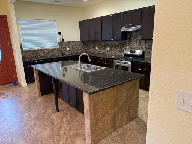 a kitchen with stainless steel appliances granite countertop a sink and a refrigerator