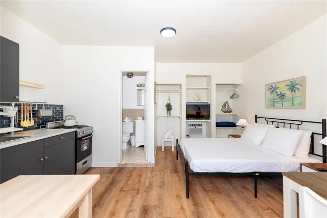 a living room with stainless steel appliances kitchen island granite countertop a stove a sink dishwasher and a refrigerator with wooden floor