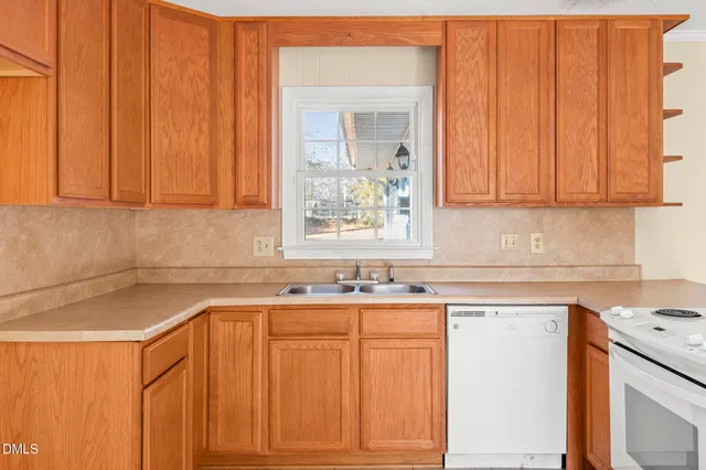 a kitchen with granite countertop white cabinets stainless steel appliances a sink and a window