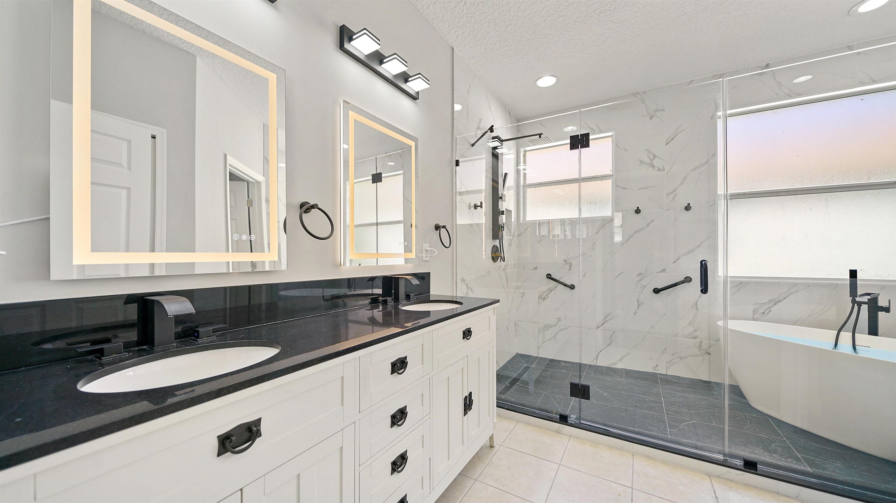 a bathroom with a granite countertop double vanity sink a mirror and a bathtub