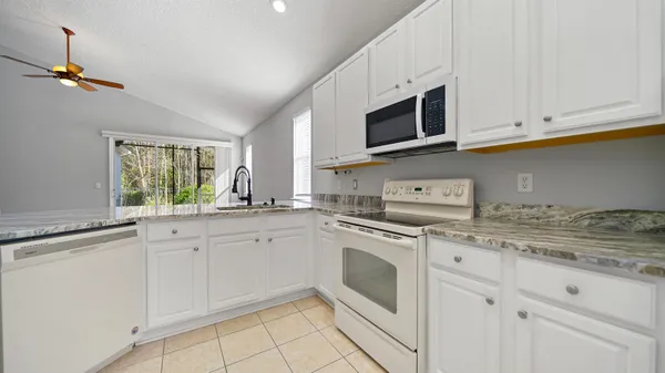 a kitchen with granite countertop white cabinets stainless steel appliances and a sink