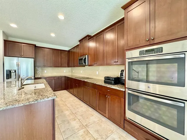 a kitchen with kitchen island granite countertop wooden cabinets a sink and a stove