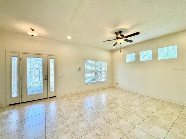 a view of a livingroom with a chandelier fan and windows