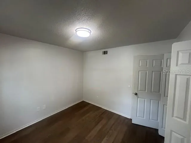 an empty room with wooden floor and cabinet