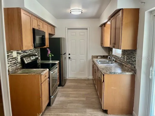 a kitchen with a stove top oven a sink and a refrigerator