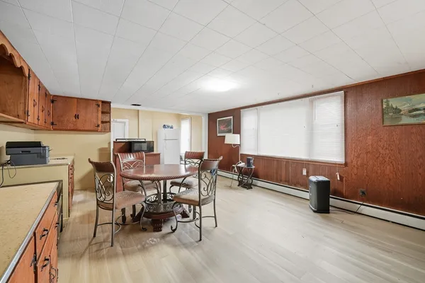 a view of dining room and livingroom with furniture wooden floor a rug a painting and a chandelier