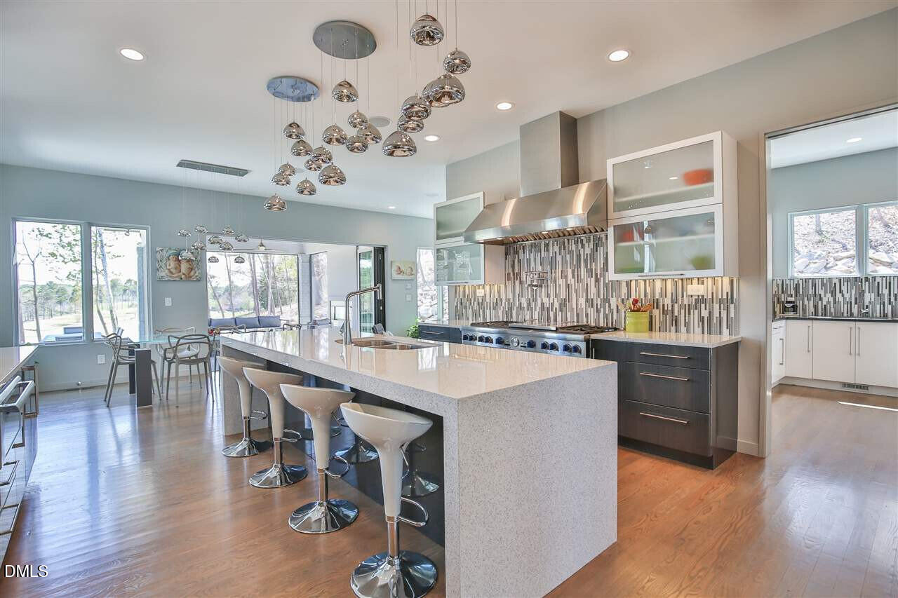 586 Poythress Road Chapel Hill, NC 27516 - Photo 4 of 33 a kitchen with stainless steel appliances granite countertop a stove oven a dining table and chairs with wooden floor