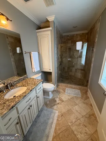 a bathroom with a granite countertop sink a toilet and shower