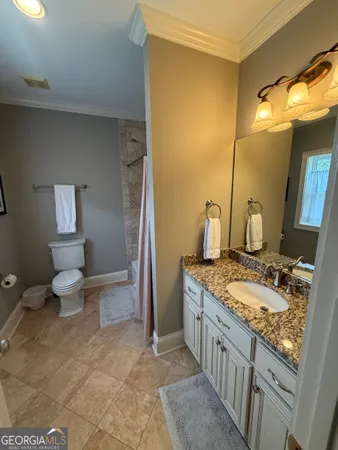 a bathroom with a granite countertop sink a toilet and a mirror