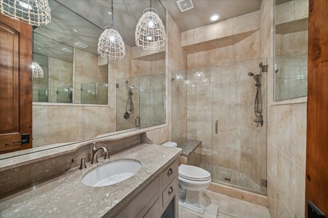 a bathroom with a granite countertop sink a toilet and shower