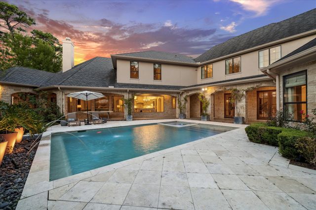 a front view of a house with a yard and a large tree
