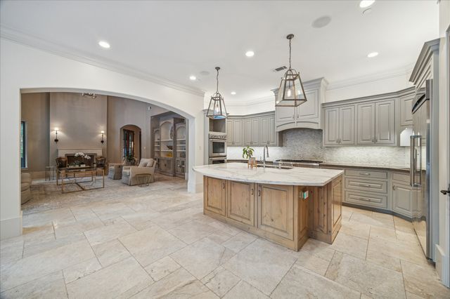 a kitchen with kitchen island granite countertop a sink and a stove top oven