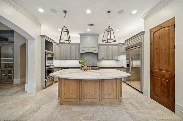 a kitchen with stainless steel appliances kitchen island a chandelier and refrigerator