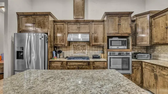 a kitchen with stainless steel appliances granite countertop a refrigerator a stove and a sink