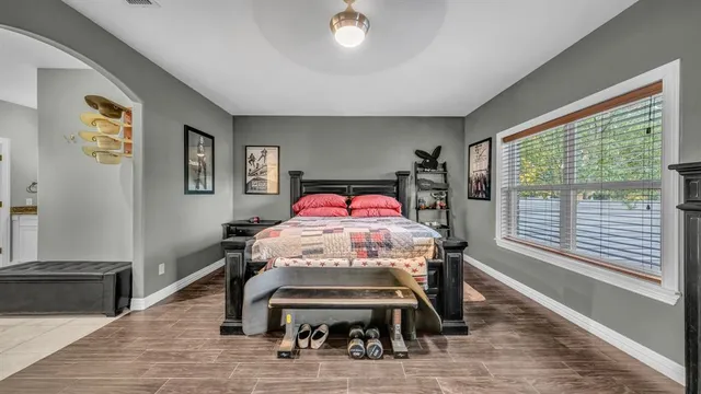 a bedroom with a bed a dresser and a large window