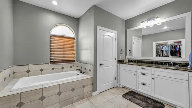 a spacious bathroom with a tub sink and mirror