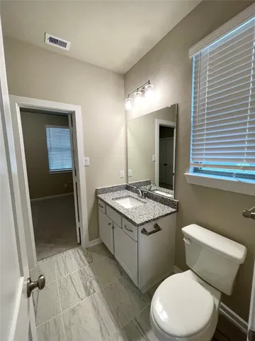 a bathroom with a granite countertop toilet sink and mirror