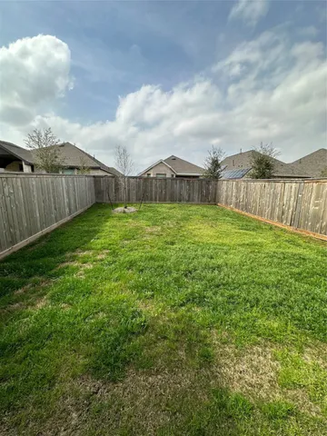 a view of a big yard with plants and wooden fence