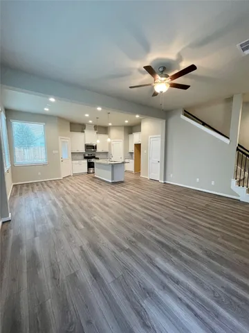 a view of a livingroom with a ceiling fan wooden floor and a ceiling fan