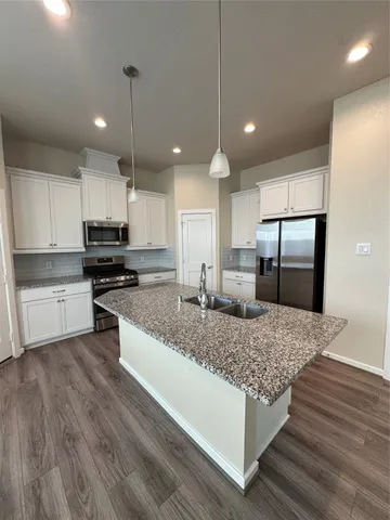 a kitchen with stainless steel appliances granite countertop a sink refrigerator and cabinets