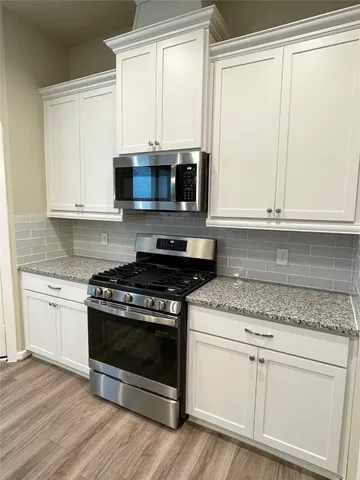 a kitchen with granite countertop white cabinets and appliances