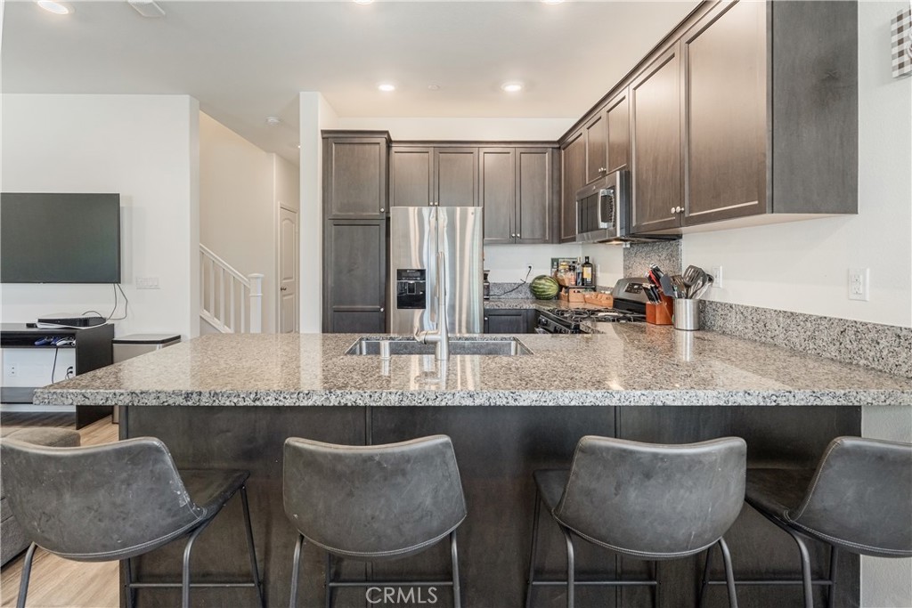 41973 Rondo Street, Unit 1203 Murrieta, CA 92562 - Photo 8 of 48 a kitchen with stainless steel appliances granite countertop a table chairs sink and cabinets
