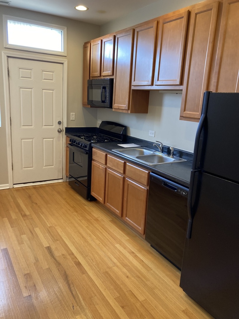 4042 South Calumet Avenue, Unit 3S Chicago, IL 60653 - Photo 3 of 11 a kitchen with granite countertop wooden cabinets and a stove top oven