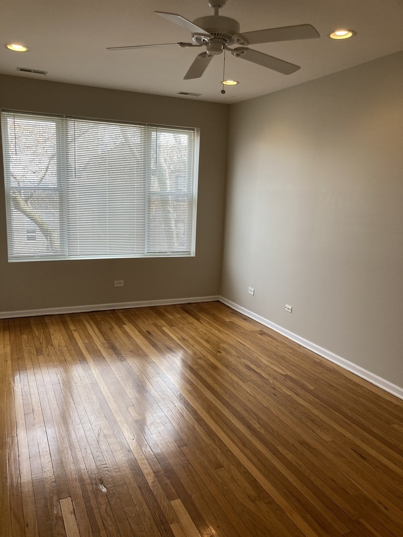 4042 South Calumet Avenue, Unit 3S Chicago, IL 60653 - Photo 7 of 11 an empty room with wooden floor fan and windows