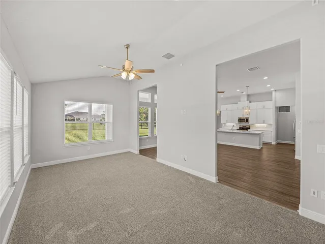 a large white kitchen with large window and wooden floor