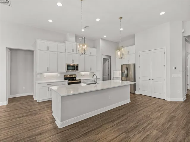 a large white kitchen with a large counter top space stainless steel appliances and a window