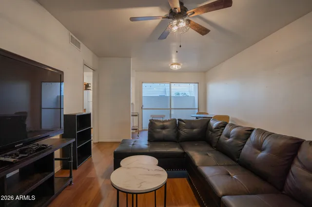 a living room with furniture a ceiling fan and a flat screen tv
