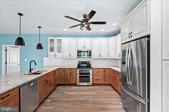 a kitchen with stainless steel appliances granite countertop a refrigerator a sink a stove and a refrigerator