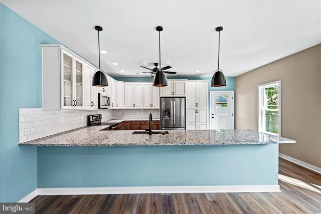 a view of a kitchen with kitchen island a sink wooden floor and window