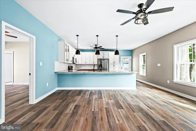 a view of a kitchen with wooden floor and a ceiling fan