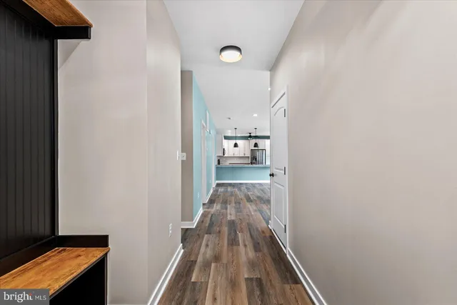 a view of a hallway with wooden floor and a bathroom