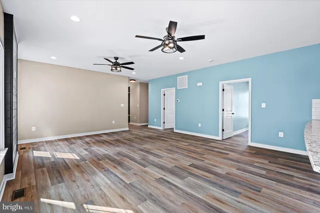 a view of empty room with wooden floor and ceiling fan