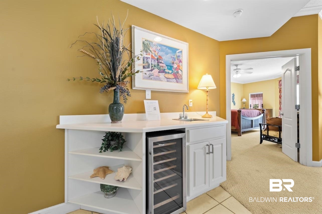 27770 Canal Road, Unit 2502 Orange Beach, AL 36561 - Photo 13 of 55 Indoor wet bar featuring light carpet, beverage cooler, white cabinetry, light tile patterned floors, and open shelves