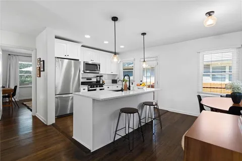 a kitchen with stainless steel appliances granite countertop a refrigerator a oven a sink a stove and white cabinets with wooden floor