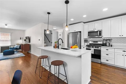 a kitchen with stainless steel appliances granite countertop a stove a sink a refrigerator a microwave oven with a dining table and chairs with wooden floor