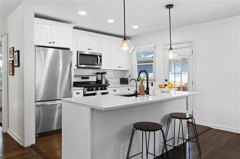 a kitchen with stainless steel appliances a refrigerator a sink a stove a dining table and chairs