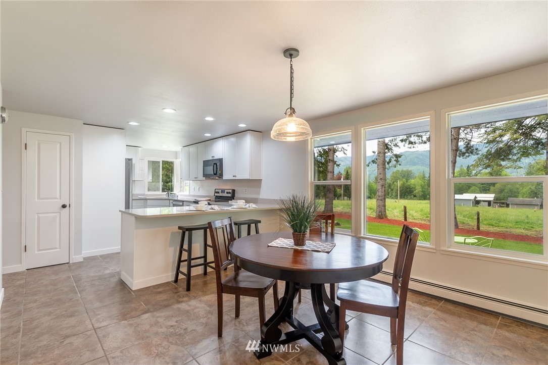 4086 Linnell Road Deming, WA 98244 - Photo 3 of 38 a kitchen with a dining table chairs and white cabinets