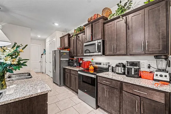 a kitchen with stainless steel appliances kitchen island granite countertop a refrigerator a stove top oven a sink and dishwasher