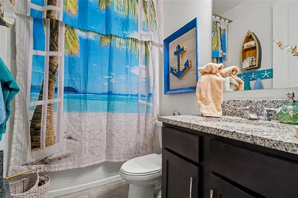 a bathroom with a granite countertop sink and a toilet