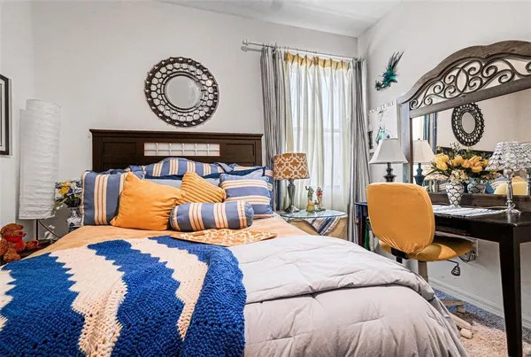 a bedroom with bed and a chair with mirror